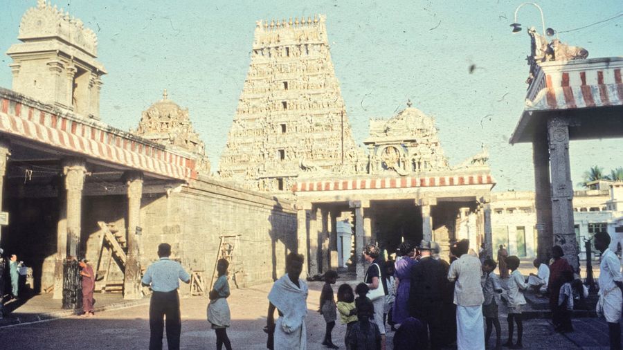 The painted gopuram gateway towers of the Kapaleeshwarar Temple in Mylapore, Chennai, covered in tiers of colourful Dravidian deity sculptures against a blue sky