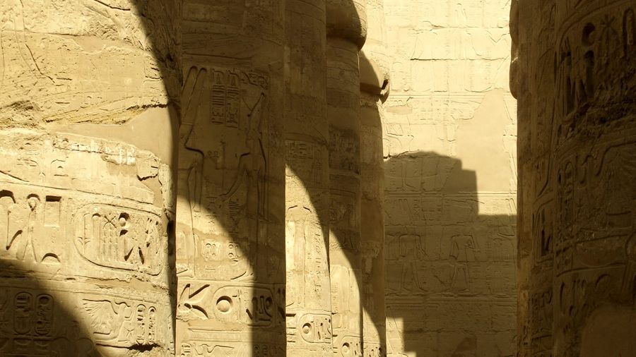 Sunlight and shadow falling across the towering hieroglyph-carved columns of the Great Hypostyle Hall at Karnak Temple in Luxor, Egypt