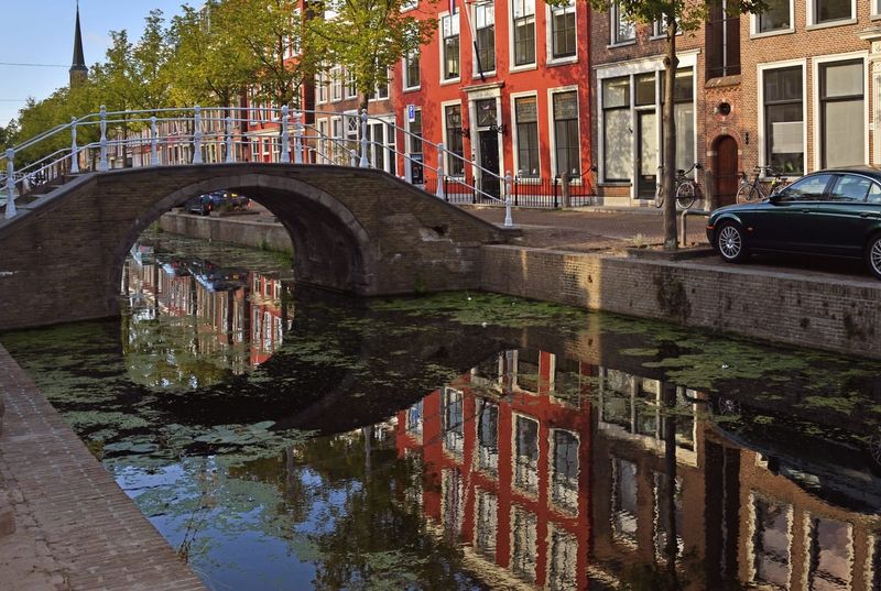 A tree-lined canal in the old centre of Delft with brick gabled houses