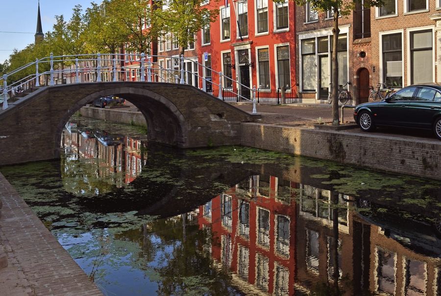 A tree-lined canal in the old centre of Delft with brick gabled houses