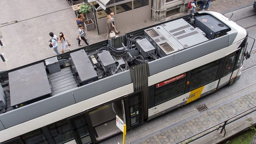 A De Lijn tram on route 1 to Wondelgem passing pedestrians on the cobblestones in central Ghent