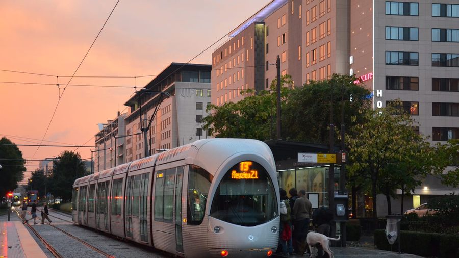 A red TCL Citadis tram on line T3 standing at the Gare Part-Dieu Villette stop in Lyon