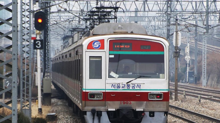 A Seoul Metro Line 1 train pulling away from a station platform in the city