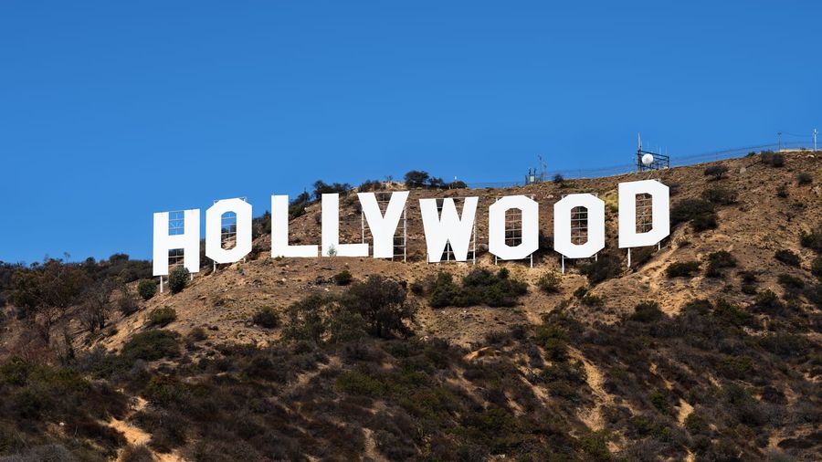 The white Hollywood Sign spelling out its letters across the brush-covered slope of Mount Lee under a deep blue sky in Los Angeles