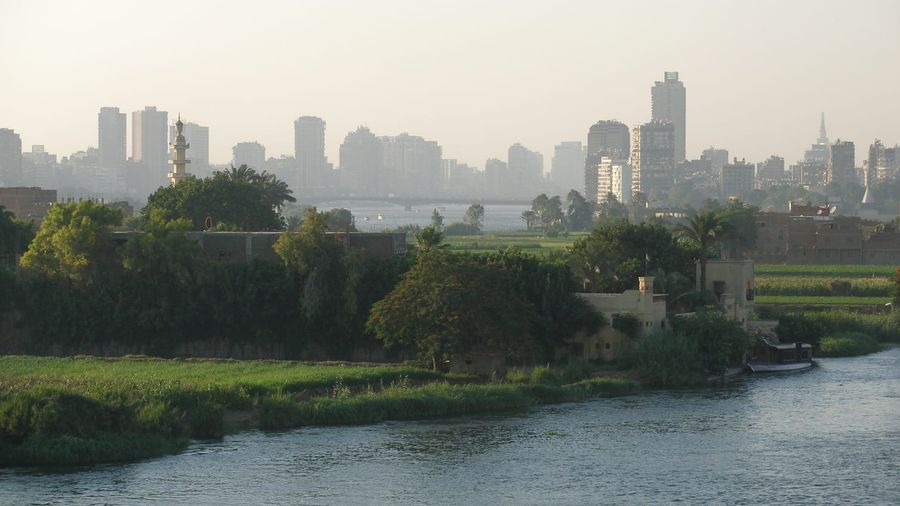 The Cairo skyline of towers and minarets stretching along the far bank of the Nile River under a hazy afternoon sky
