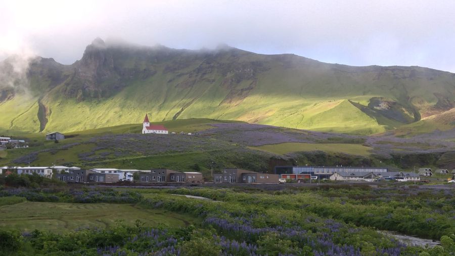 The red-roofed Víkurkirkja church on the hill above Vík í Mýrdal, with the village and black-sand South Coast beyond