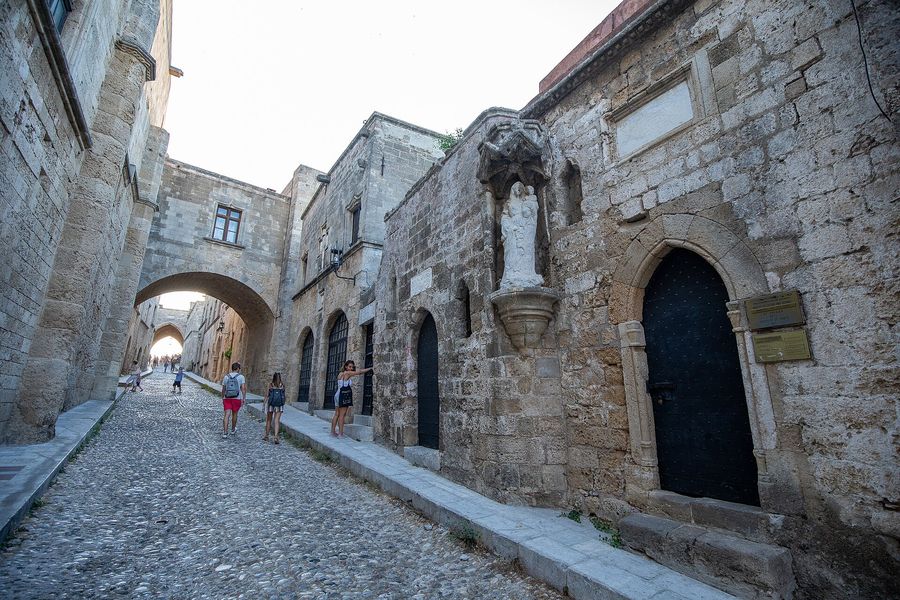 The cobbled, arched Street of the Knights running between honey-coloured medieval stone auberges in the Old Town of Rhodes, Greece