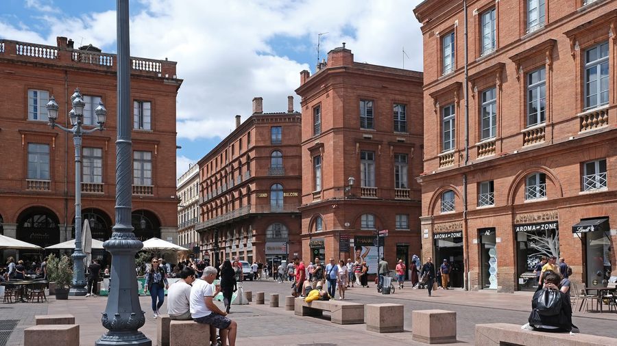 The Place du Capitole in Toulouse, its 18th-century Capitole façade of pink brick and pale stone facing the open square inlaid with the bronze Occitan cross