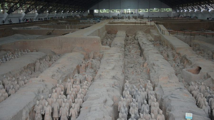 Rows of life-size terracotta warrior statues standing in an excavation pit at the Terracotta Army near Xian, China